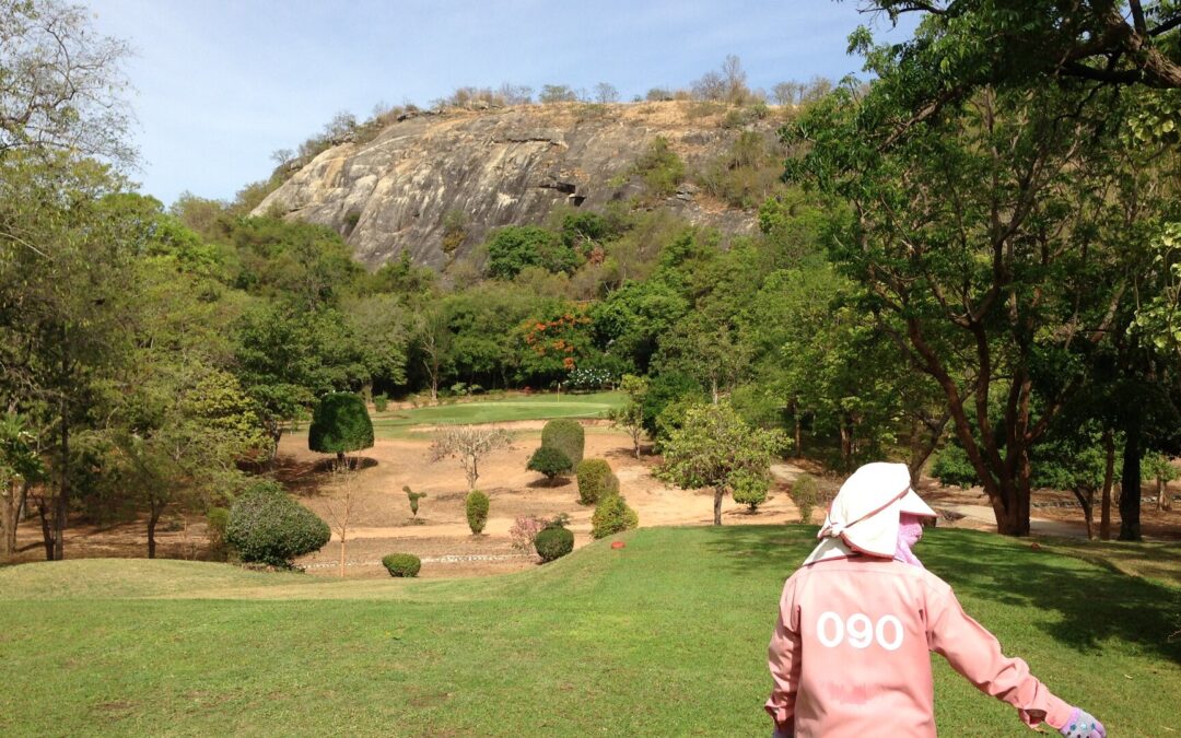 Caddie walking a fairway at Royal Hua Hin Golf Course with the rocky hillside behind